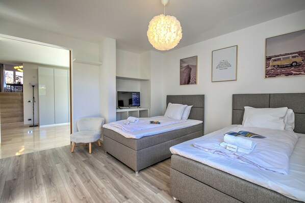 A modern hotel room with a bed, bedside table, chair, and a desk with a computer. - Lugano Lake View Villa w. Private Pool (Lugano)