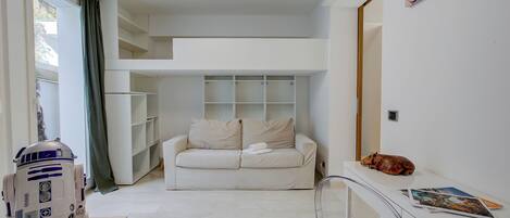 A modern living room with a white sofa, a small table, and a clear glass partition.