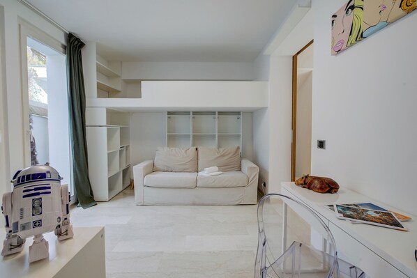 Un salon moderne avec un canapé blanc, une petite table et une cloison en verre transparent.