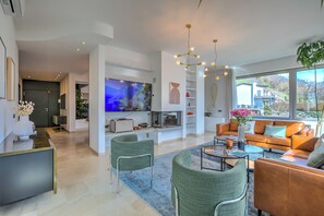 A modern living room with a large flat-screen TV, comfortable seating, a coffee table, and a view of the outside. - Lugano Lake View Villa w. Private Pool (Lugano)