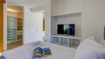 A hotel room with a bed, a TV on a stand, a bookshelf, and a walk-in closet.