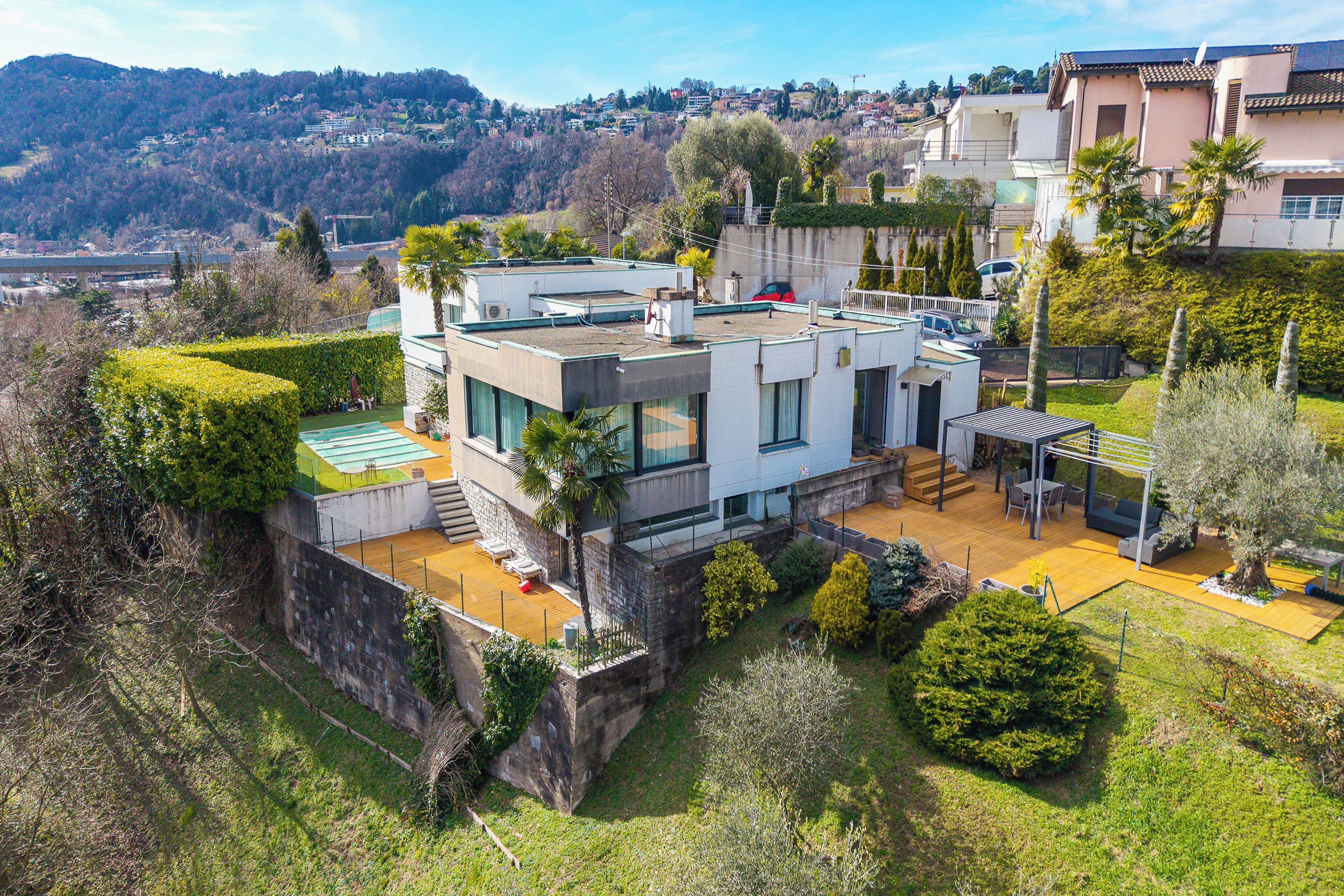 A modern house with a flat roof, large windows, and a well-maintained garden.