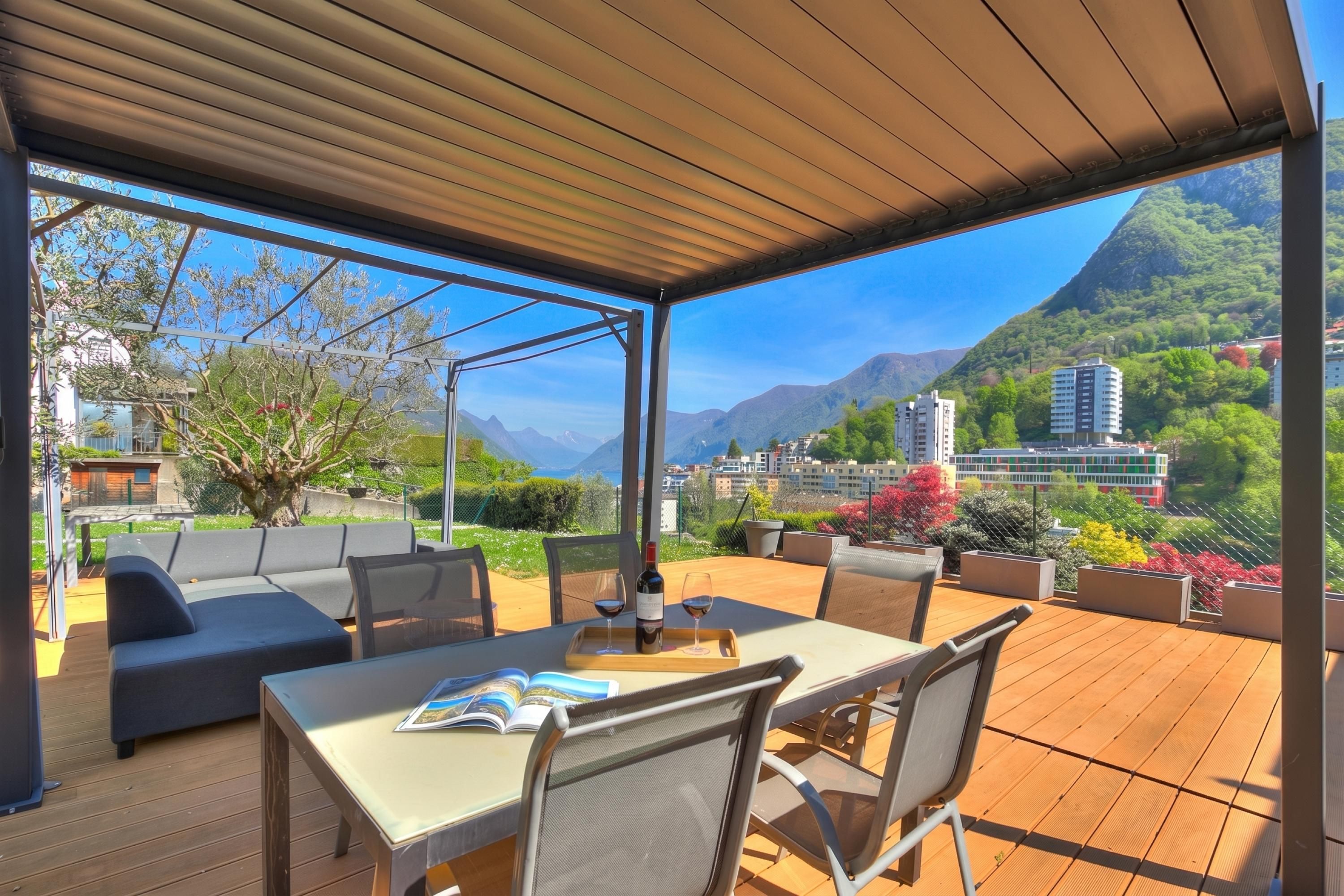 Un patio al aire libre con una mesa, sillas y un sofá, con vistas a un paisaje montañoso.