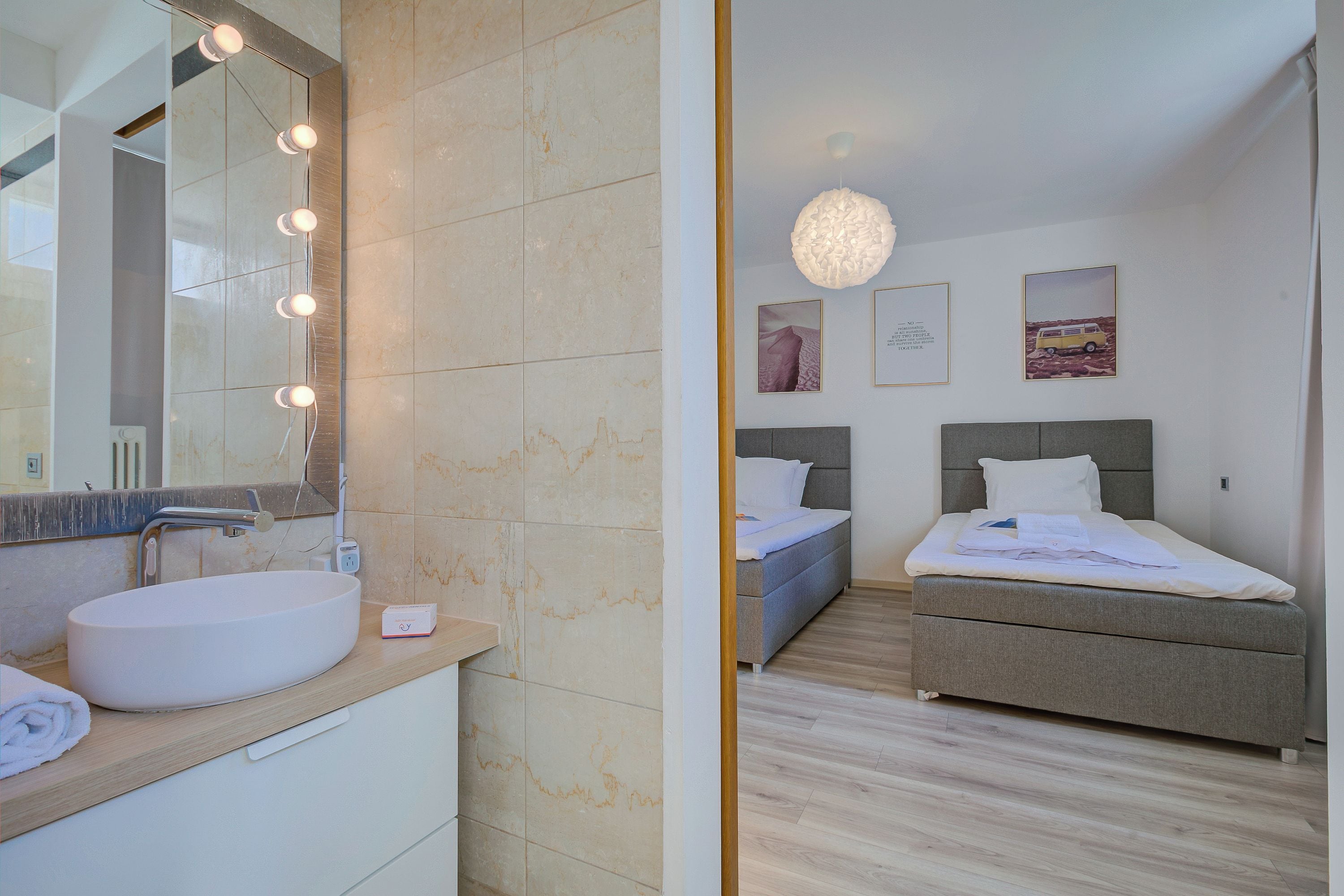 Une salle de bain moderne avec un grand miroir, un lavabo rond et une commode sur laquelle est posée une serviette.