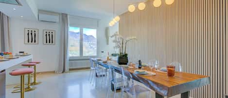 A modern dining area with a wooden table, clear chairs, and a decorative light fixture.
