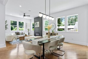 A modern living room with a dining area, large windows, and a ceiling fan. - Spacious Executive Home Near Airport & Downtown Atlanta (College Park)