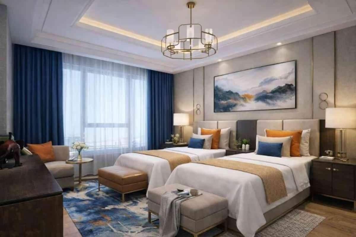 Habitación de hotel con dos camas, un sofá, un escritorio y una araña.