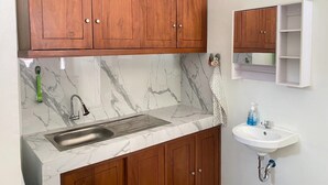 Une cuisine avec des meubles en bois, un plan de travail en marbre, un évier et un meuble à pharmacie blanc fixé au mur.