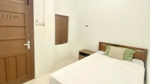 Une chambre à coucher comprenant un lit, une tête de lit en bois, une table de chevet, une porte et un appareil de climatisation.