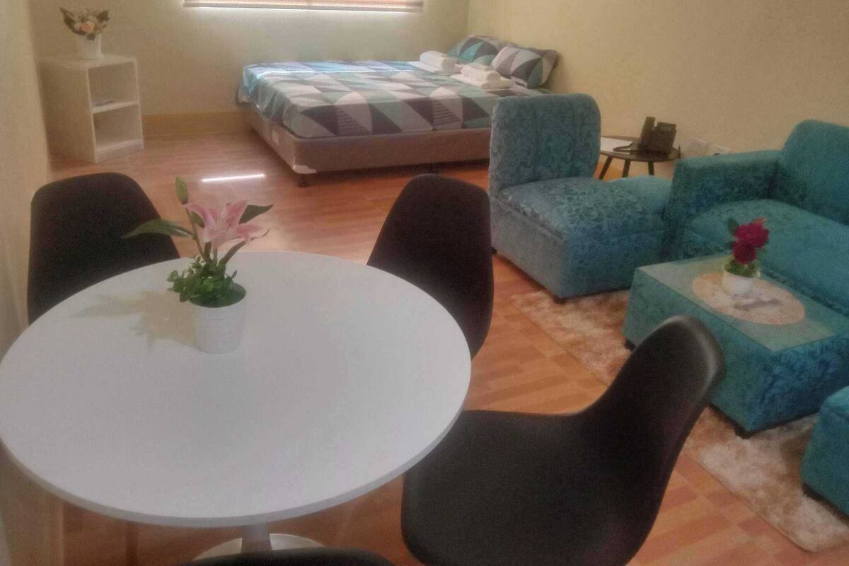 Een kamer met een bed, een bank, een eettafel en stoelen.