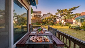 Ein Garten-BBQ-Arrangement mit Grill, Esstisch und Gartenmöbeln.