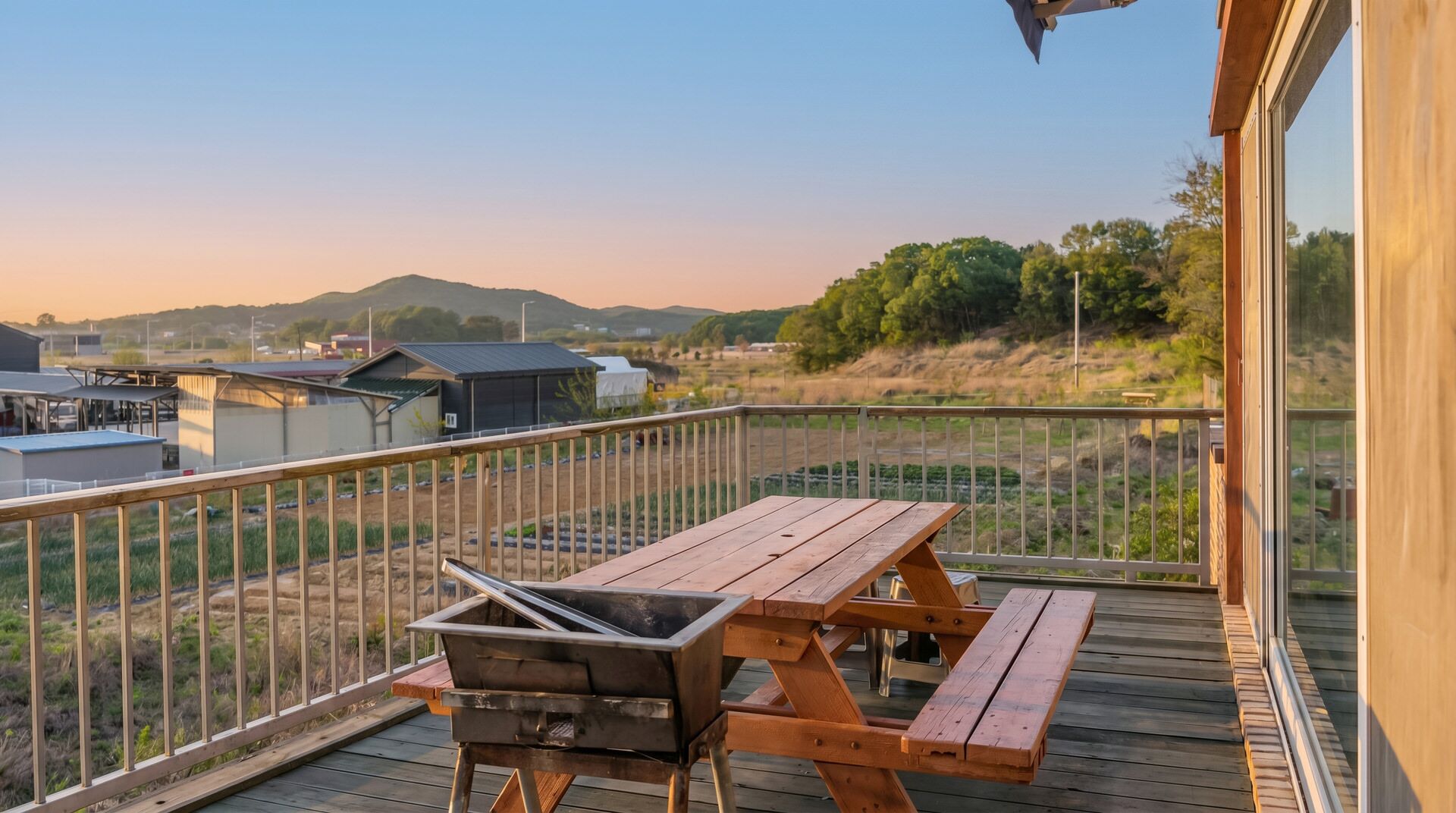 Un balcone con griglia, tavolo da picnic e vista su un paesaggio rurale.