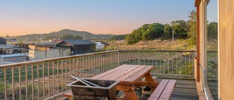 Un balcone con griglia, tavolo da picnic e vista su un paesaggio rurale.