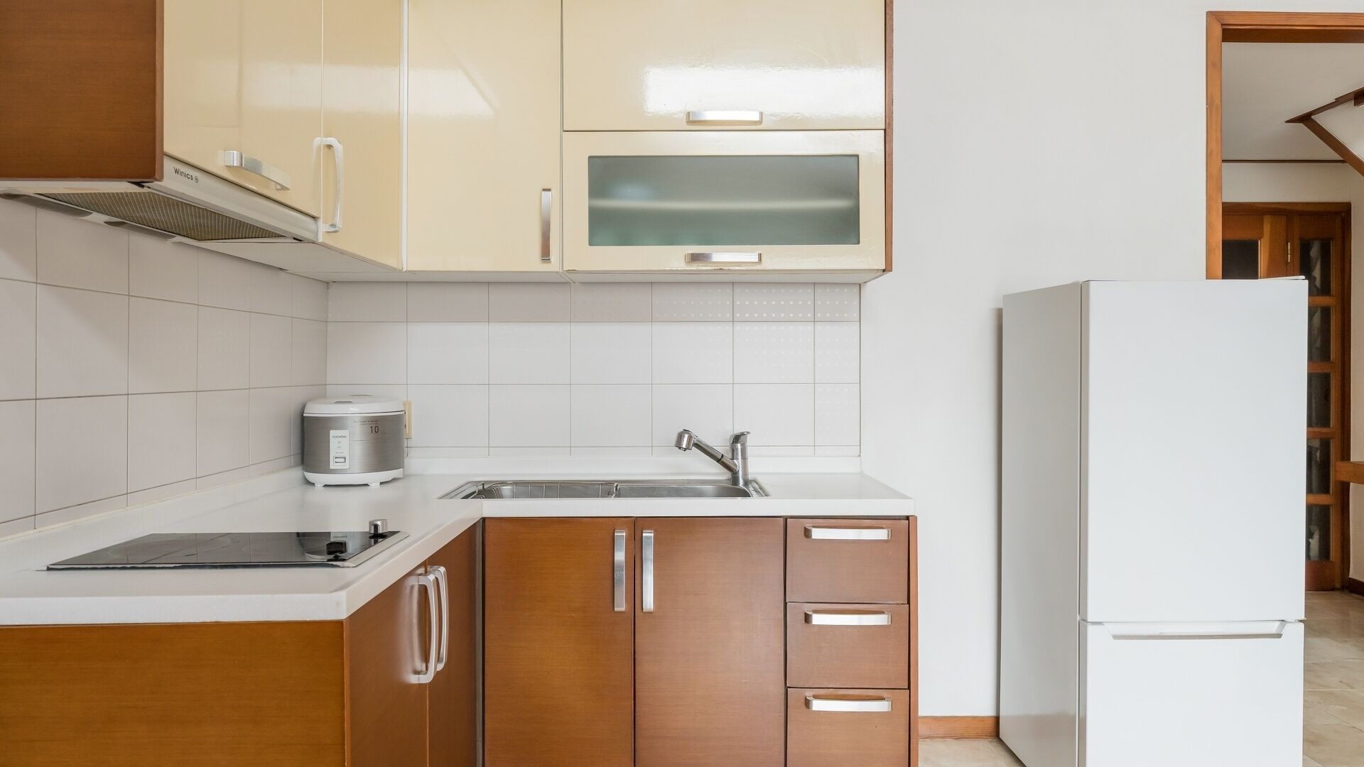 A kitchen with wooden cabinets, a stainless steel sink, and a white refrigerator.