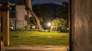 A nighttime view of a grassy area with a tree, a rock, and a building in the background. - Daebu-do, White Island Pension (Ansan)