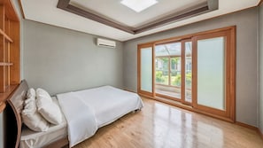 A bedroom with a bed, a ceiling fan, and a sliding glass door leading to a balcony.