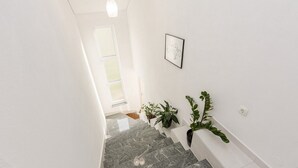 A staircase with a white wall, a framed picture, and potted plants. - Flora Maris Pool Apartments (Privlaka)