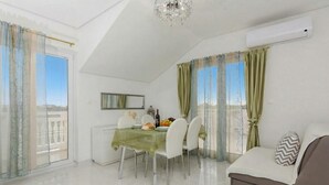 A modern living room with a dining area, a sofa, and a chandelier. - Flora Maris Pool Apartments (Privlaka)