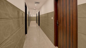 A hallway with a wooden door on the right, tiled walls, and a ceiling with recessed lighting. - Townhouse Subharti University Meerut (Meerut)