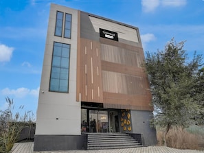 A modern townhouse with a prominent sign, large windows, and a wooden facade.