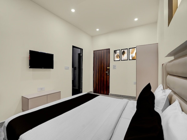 A hotel room with a bed, a TV mounted on the wall, a wardrobe, and a door.