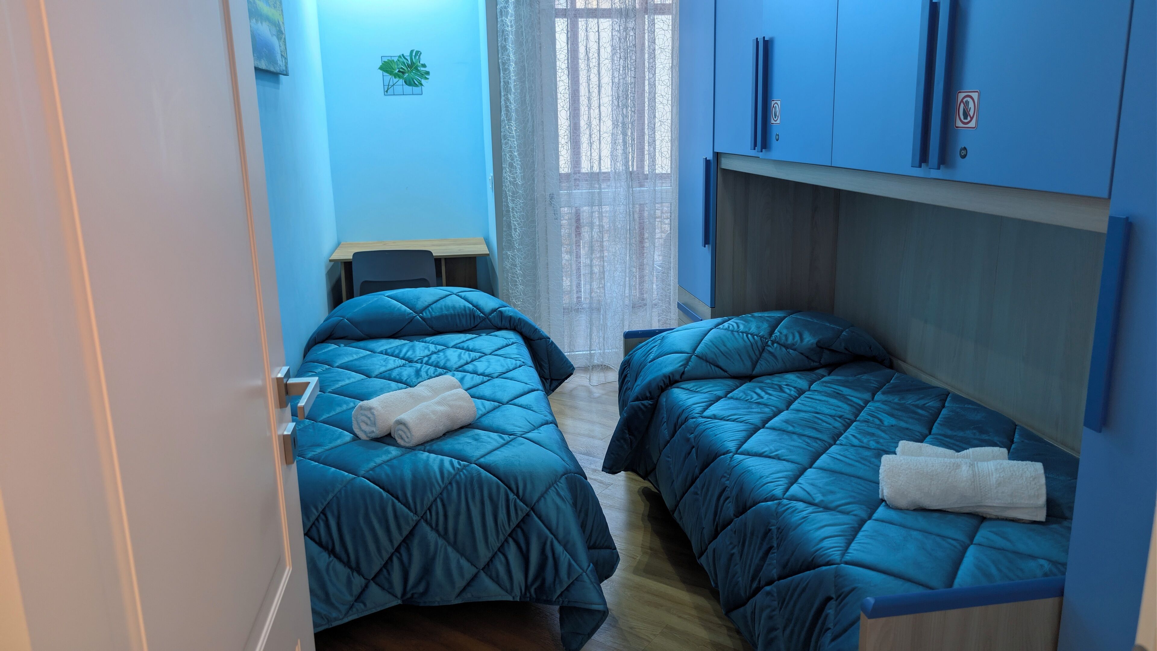 Una habitación pequeña y funcional con dos camas, un escritorio y una silla.