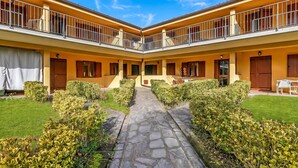 Un patio con un sendero de piedra, paredes amarillas y un edificio de dos pisos con balcones.