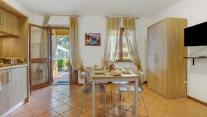 Un comedor con una mesa lista para dos personas, un televisor montado en la pared y una puerta corrediza que da a un espacio exterior.
