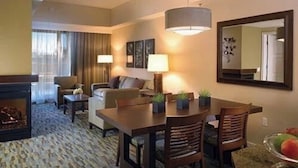 Une chambre d’hôtel dotée d’un coin repas, d’une cheminée, d’un canapé et d’un grand miroir.