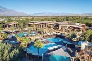 Un resort con varias piscinas, zonas de estar al aire libre y montañas al fondo.