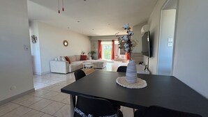 A dining area with a table, chairs, a vase, and a sofa in the background. - Quiet, friendly house for up to 6 people (Peyrehorade)