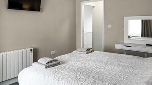 Ett hotellrum med en stor säng, en tv, en spegel och ett element.