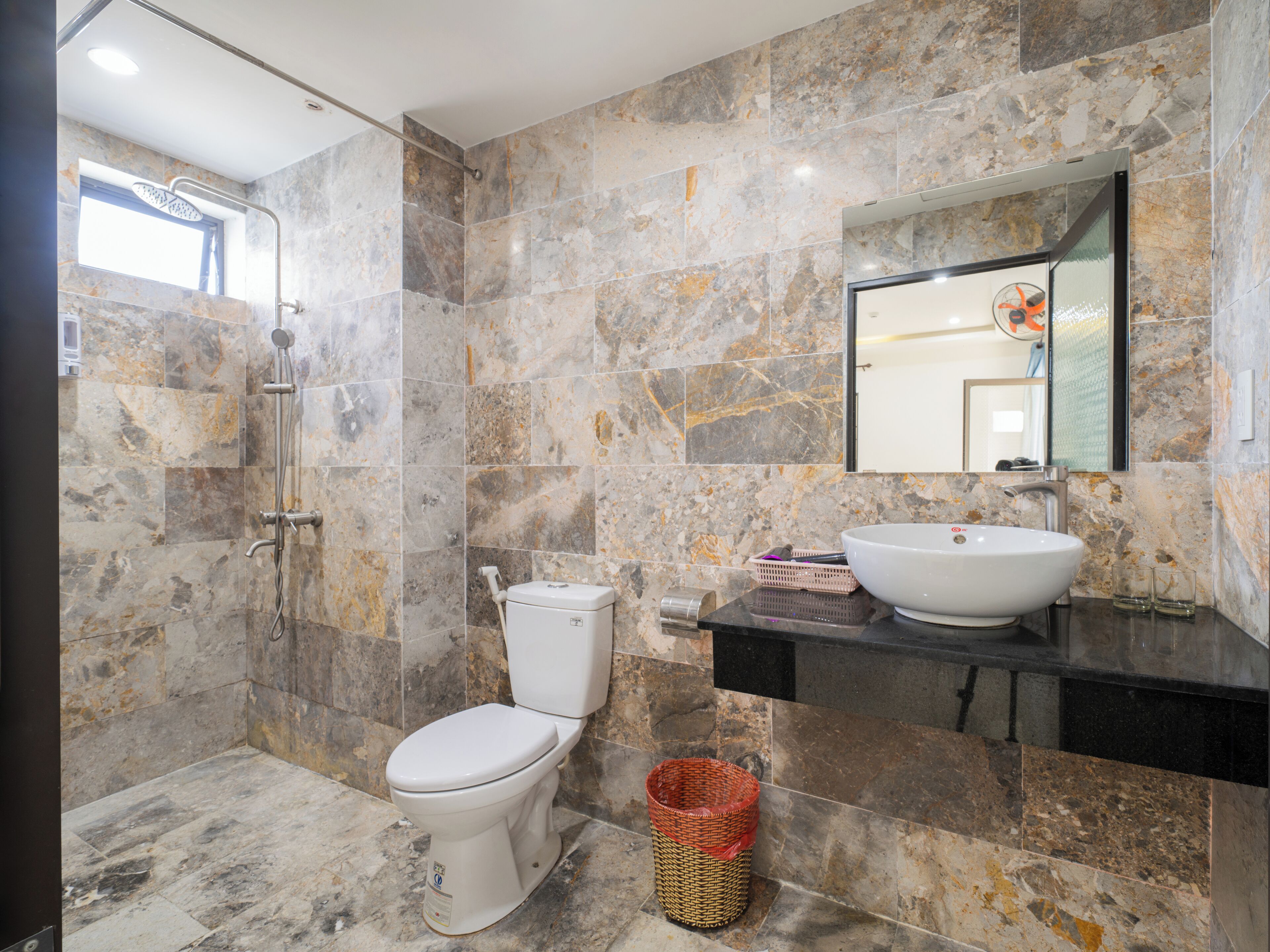 A bathroom with a toilet, a sink, a shower, and a mirror.