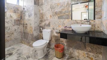 A bathroom with a toilet, a sink, a shower, and a mirror.