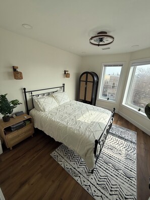 A bedroom with a bed, bedside tables, a window, and a view of the outside. - Monthly stay near Light Rail + NYC rooftop views (Jersey City)