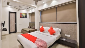 A modern hotel room with a large bed, a desk, a chair, a TV, and a ceiling fan. - Hotel O Vatva Railway Station (Ahmedabad)