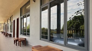A covered outdoor seating area with wooden tables and benches, large windows, and a view of greenery. - Alicia resort (Koh Rong)