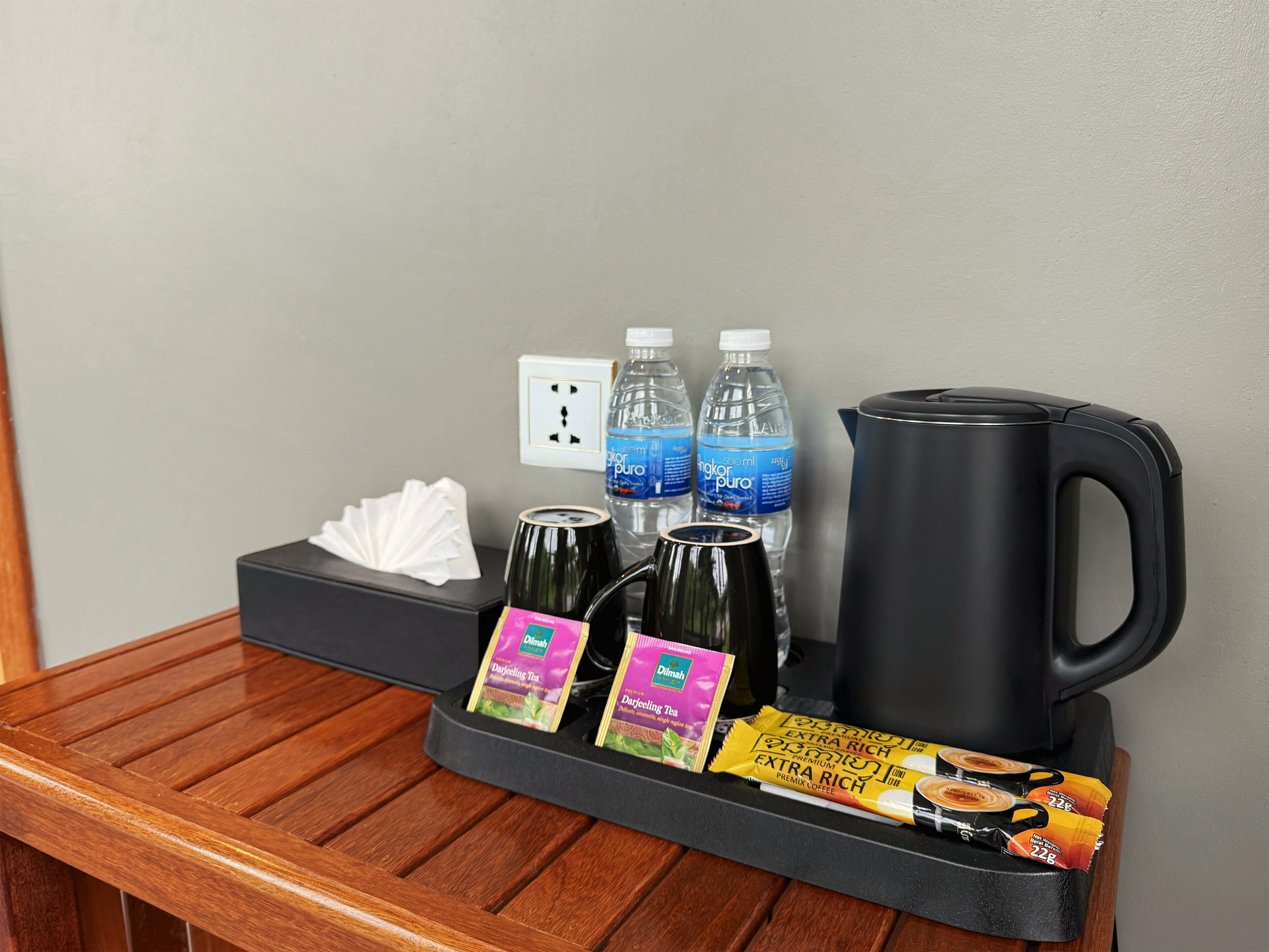 Minibar de una habitación de hotel con agua embotellada, té, café y una tetera.