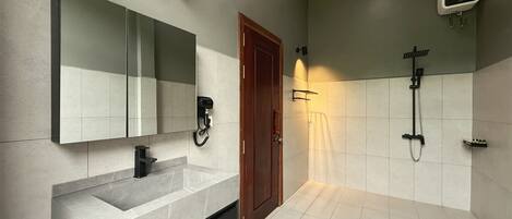 A modern bathroom with a large mirror, a built-in sink, a shower, and a towel rack.
