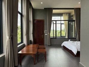 A room with a bed, a wooden table, a bench, a wardrobe, and large windows with curtains. - Alicia resort (Koh Rong)