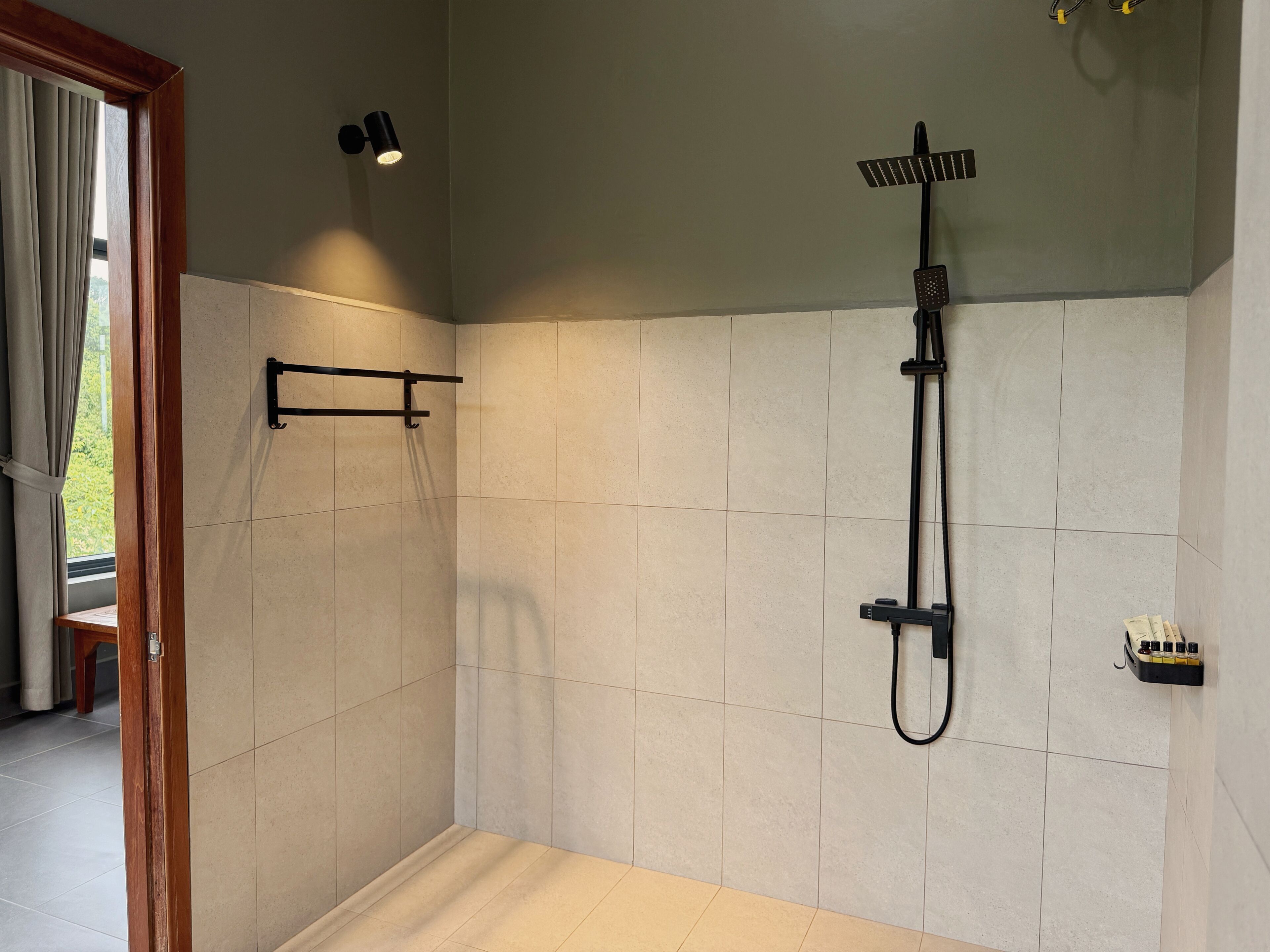 A shower area with a handheld showerhead, a towel rack, and a wall-mounted light fixture.