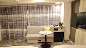 A hotel room with a sofa, a small round table, a bedside table with a kettle, and a TV. - HOTEL AMANEK Kumamoto (Kumamoto)