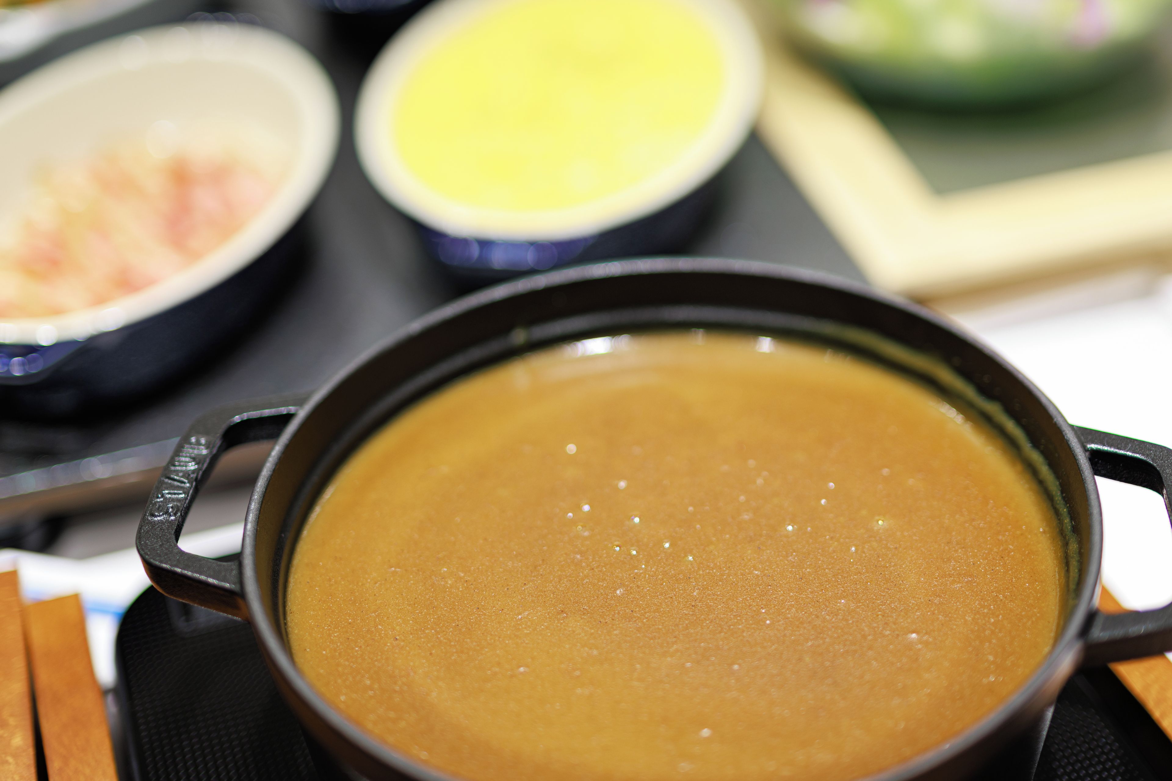 A close-up of a pot with a brown liquid, possibly soup, on a stove.