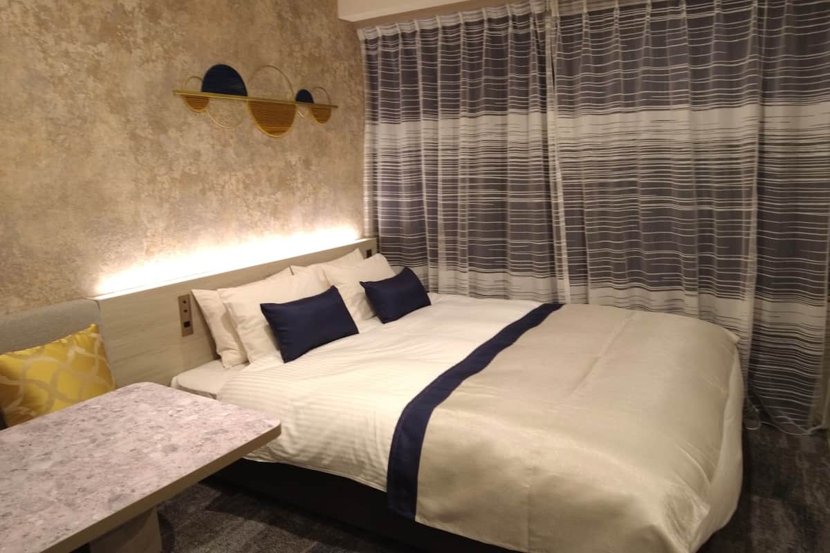 A hotel room with a bed, bedside table, and curtains.