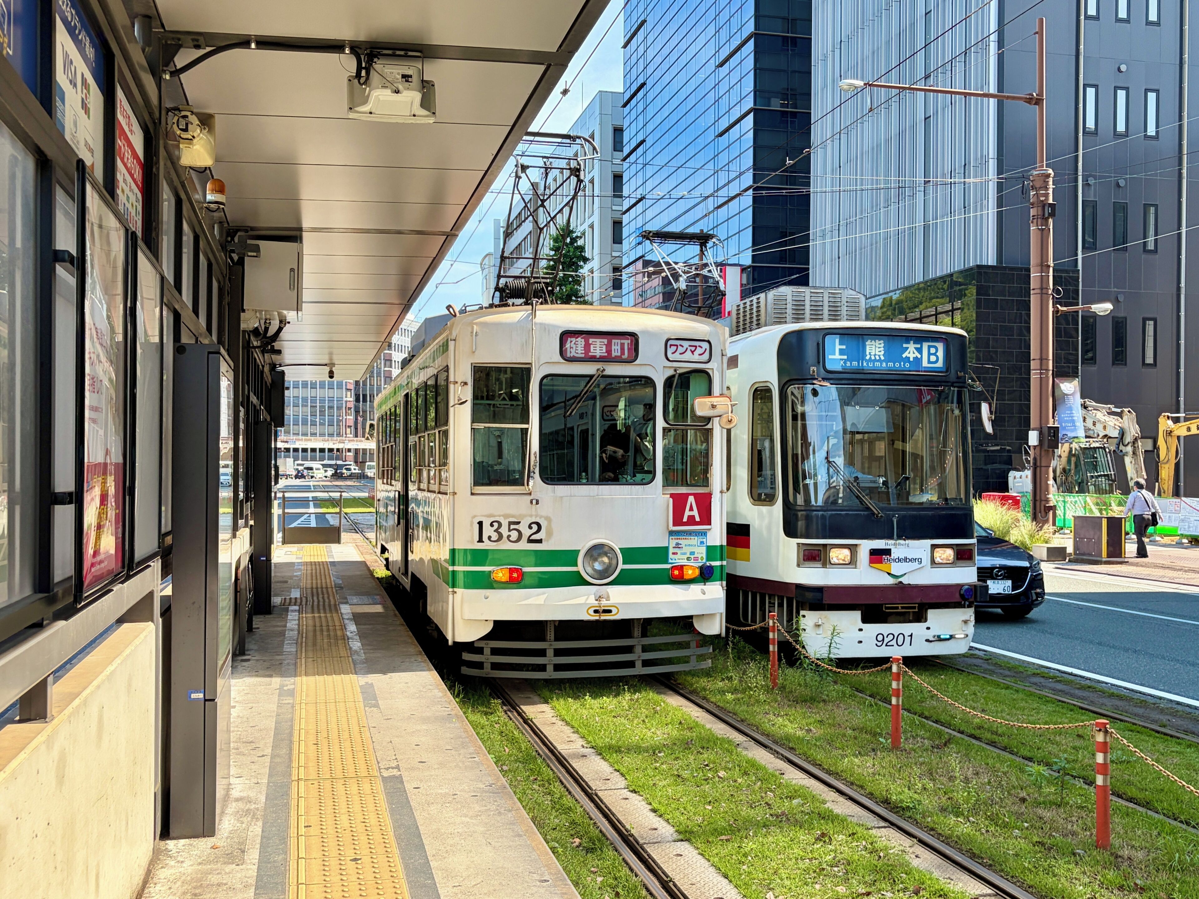 Two trains at a station platform with buildings in the background.