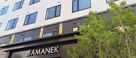 A multi-story building with a storefront labeled 'AMANEK.'
