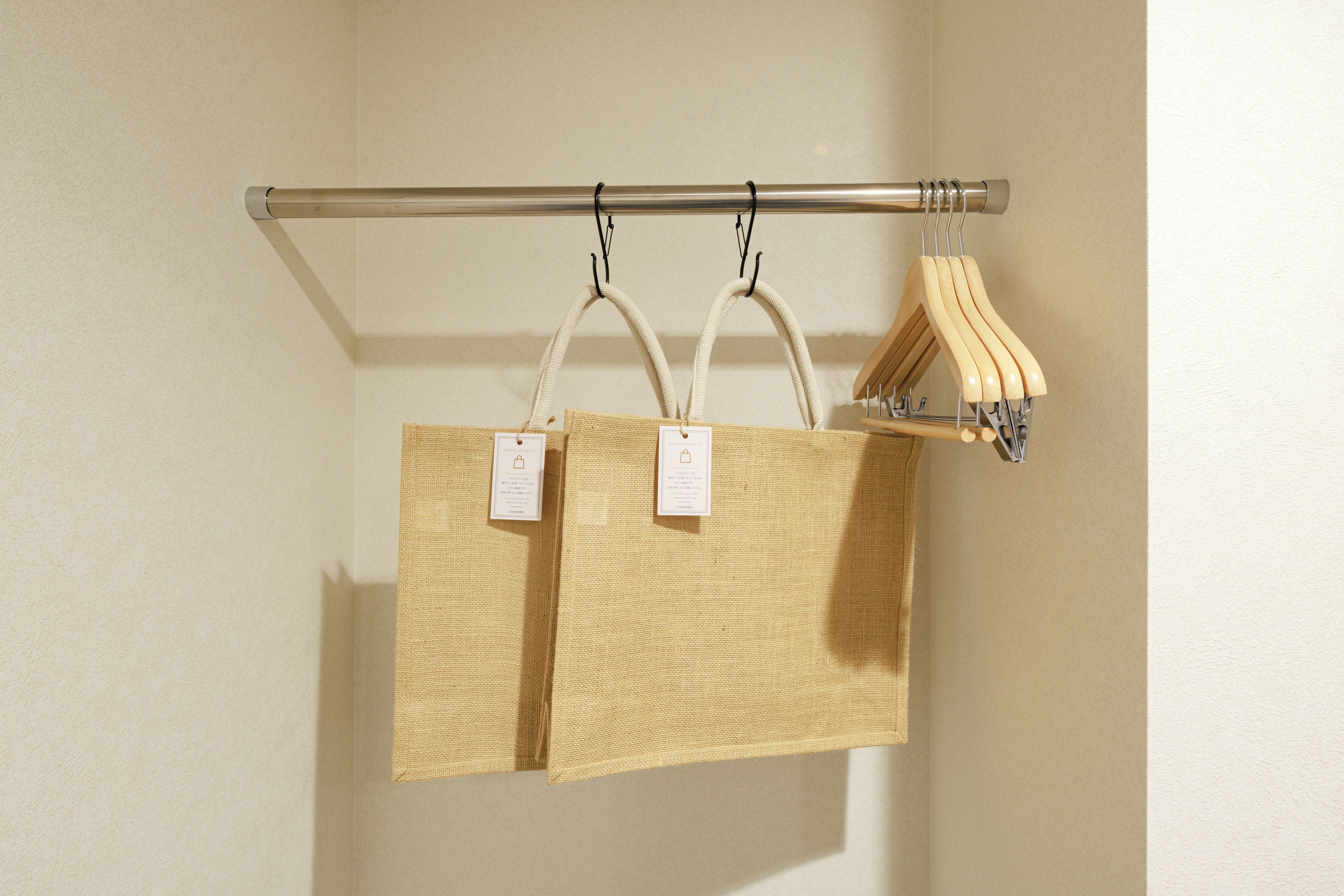 Two woven bags hanging on a metal rod, with tags attached.