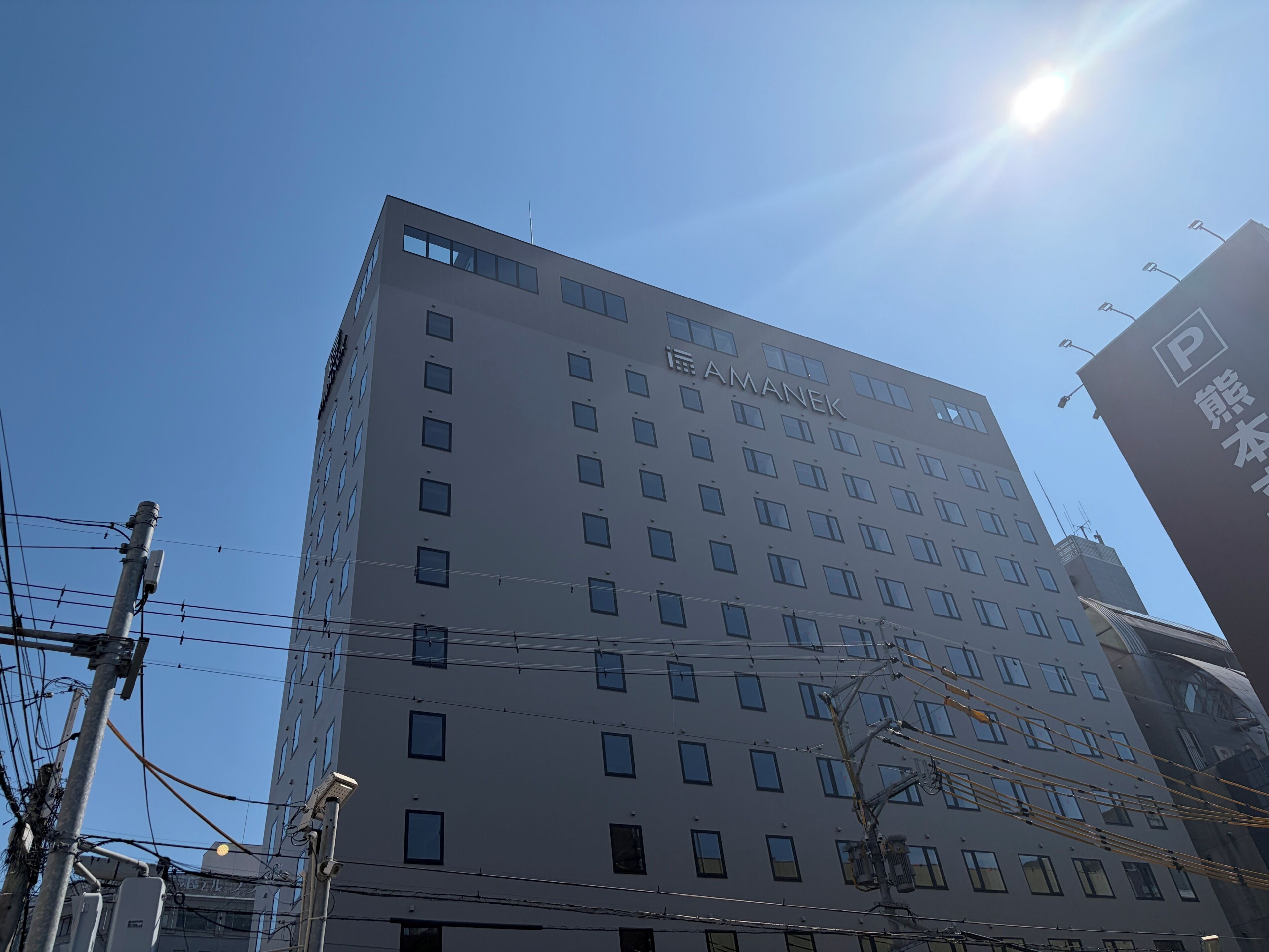 A multi-story building with the name 'AMANEK' prominently displayed on the facade.