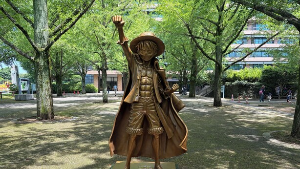 A statue of Monkey D. Luffy in a park with trees and a building in the background. - HOTEL AMANEK Kumamoto (Kumamoto)