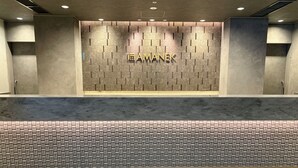 A reception area with a textured wall, a reception desk, and a patterned carpet. - HOTEL AMANEK Kumamoto (Kumamoto)